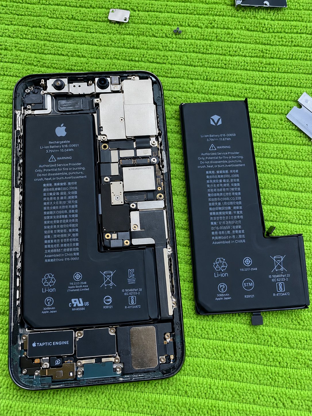 iPhone 11 Pro battery replacement in Calgary showing original Apple battery installed and third-party replacement battery alongside